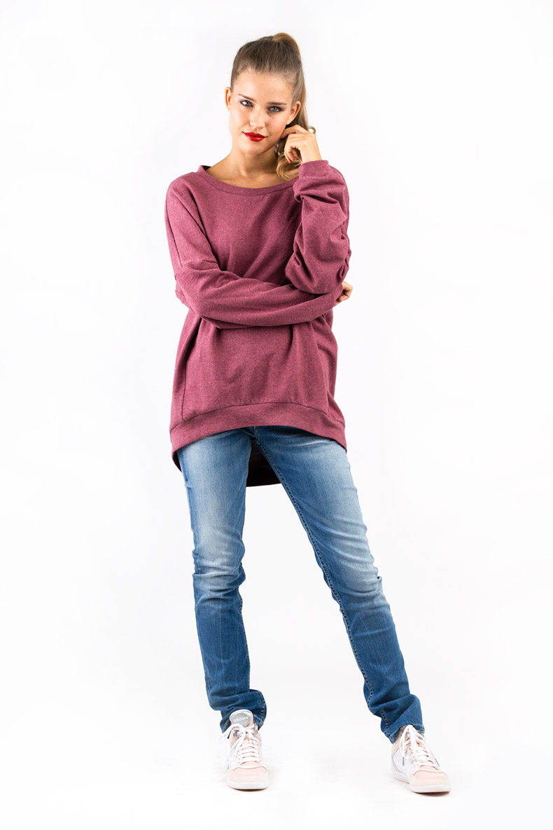 In front of a white background, a lady is posing in her self-sewn oversized shirt.
