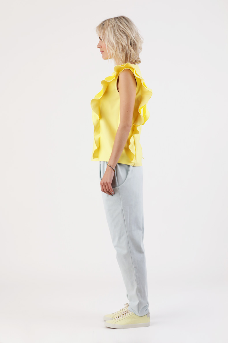 A woman is posing in her self-sewn yellow top.