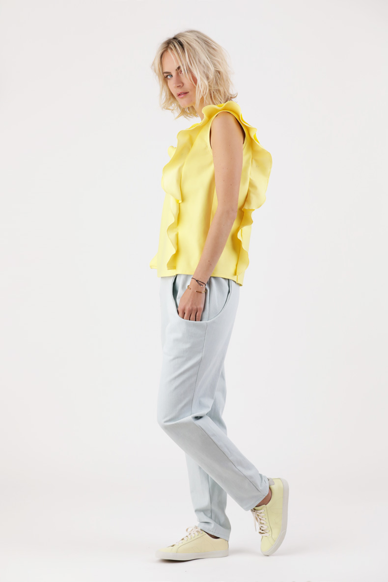 A woman wearing a yellow top and blue pants.