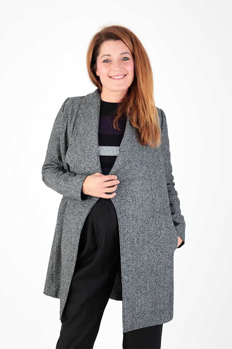 A woman is smiling while presenting her self-sewn coat.