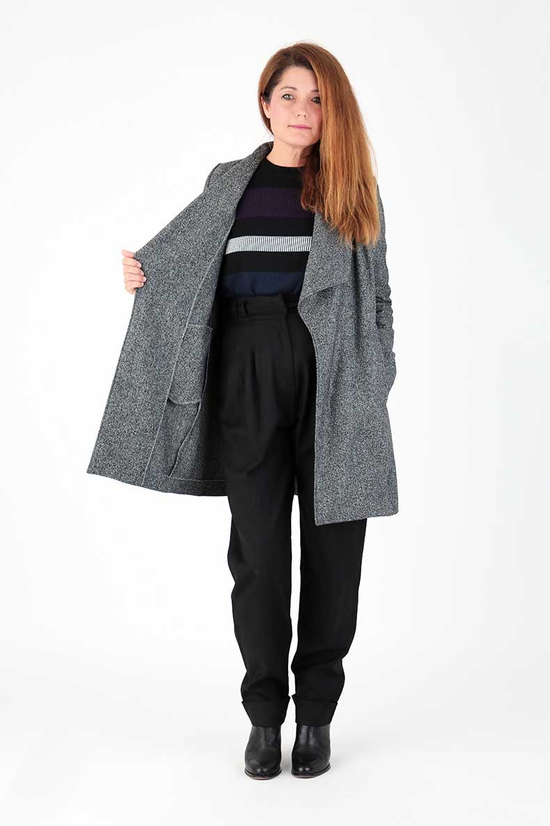 A woman is showing the inside of her gray coat.