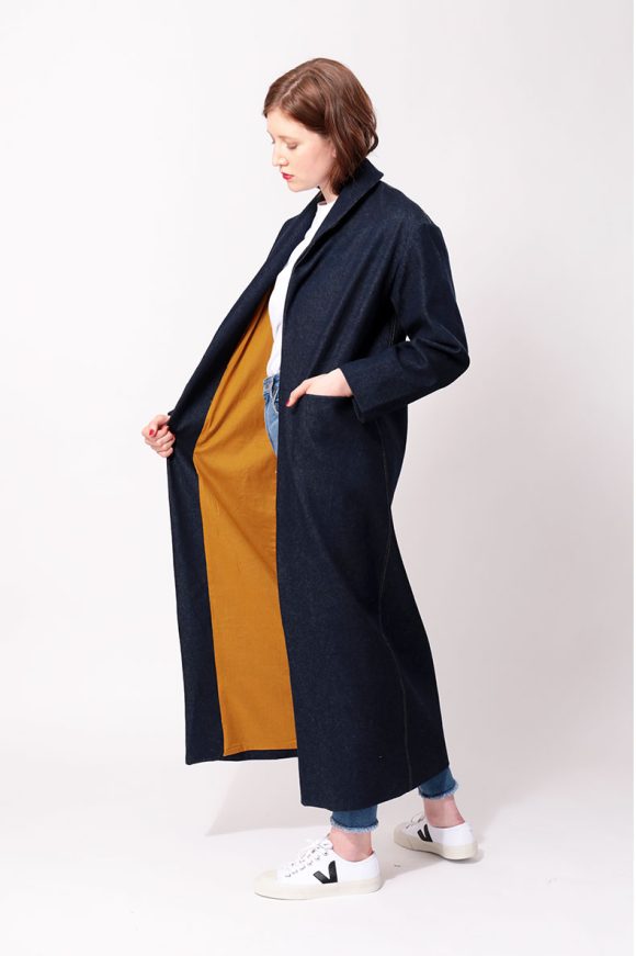 A woman is showing the inside of her blue coat.