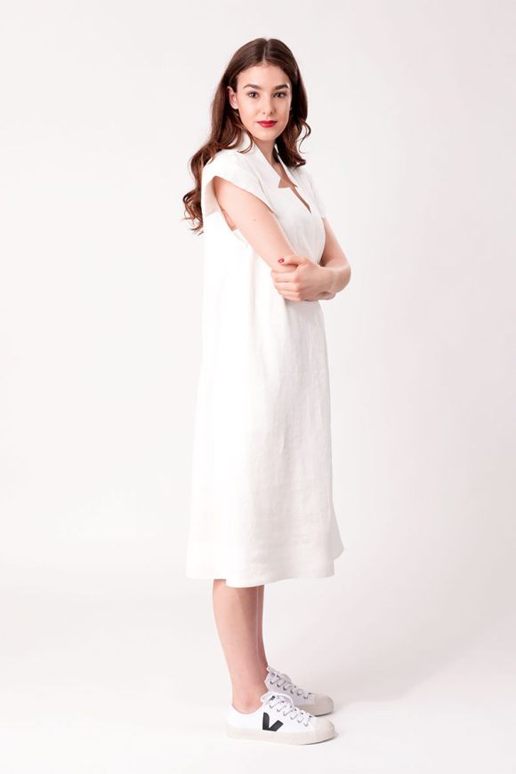 Seitenaufnahme einer lächelnden Frau welche ein weißes Kleid trägt
